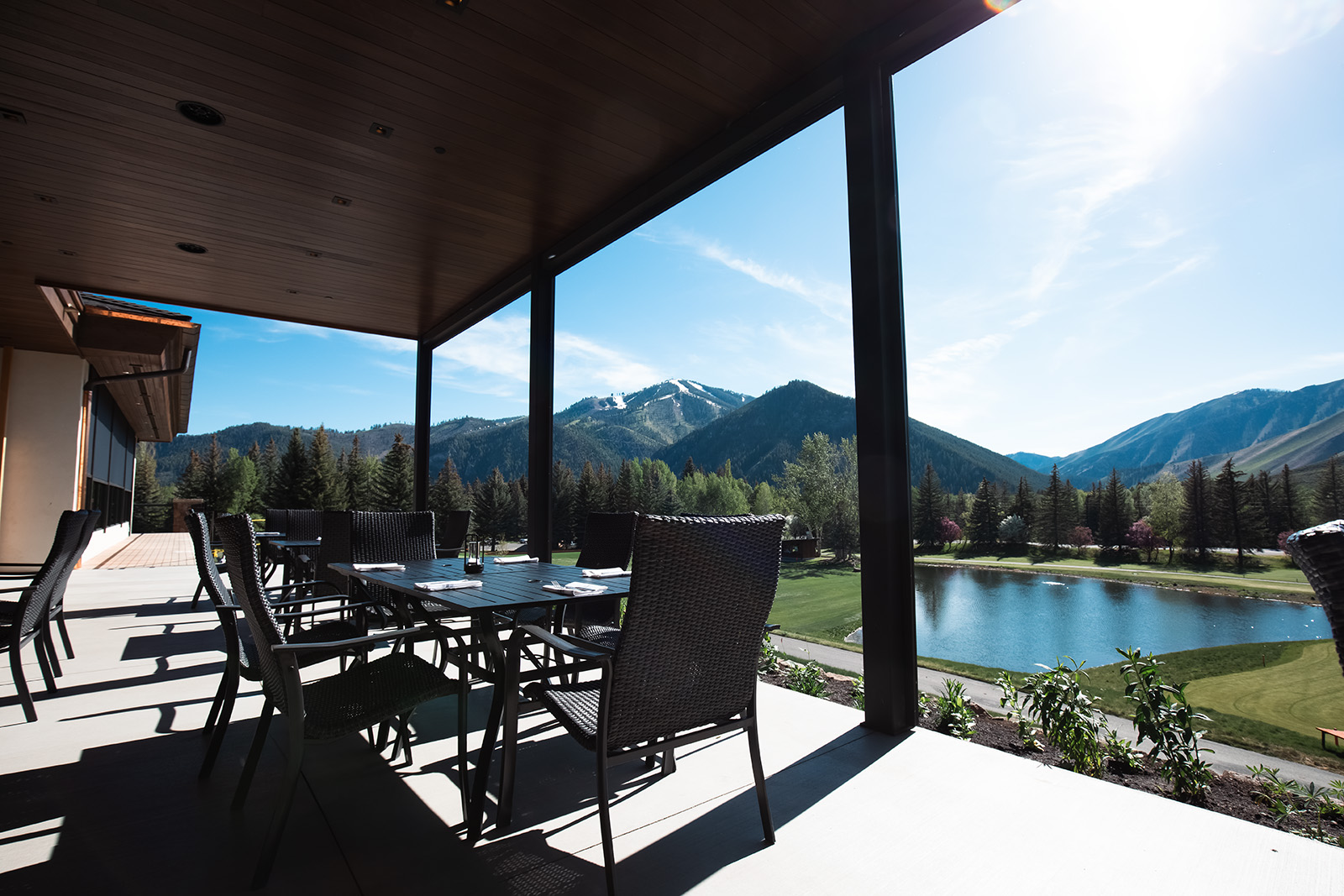 Covered patio with tables looking out at Baldy mountain and a pond