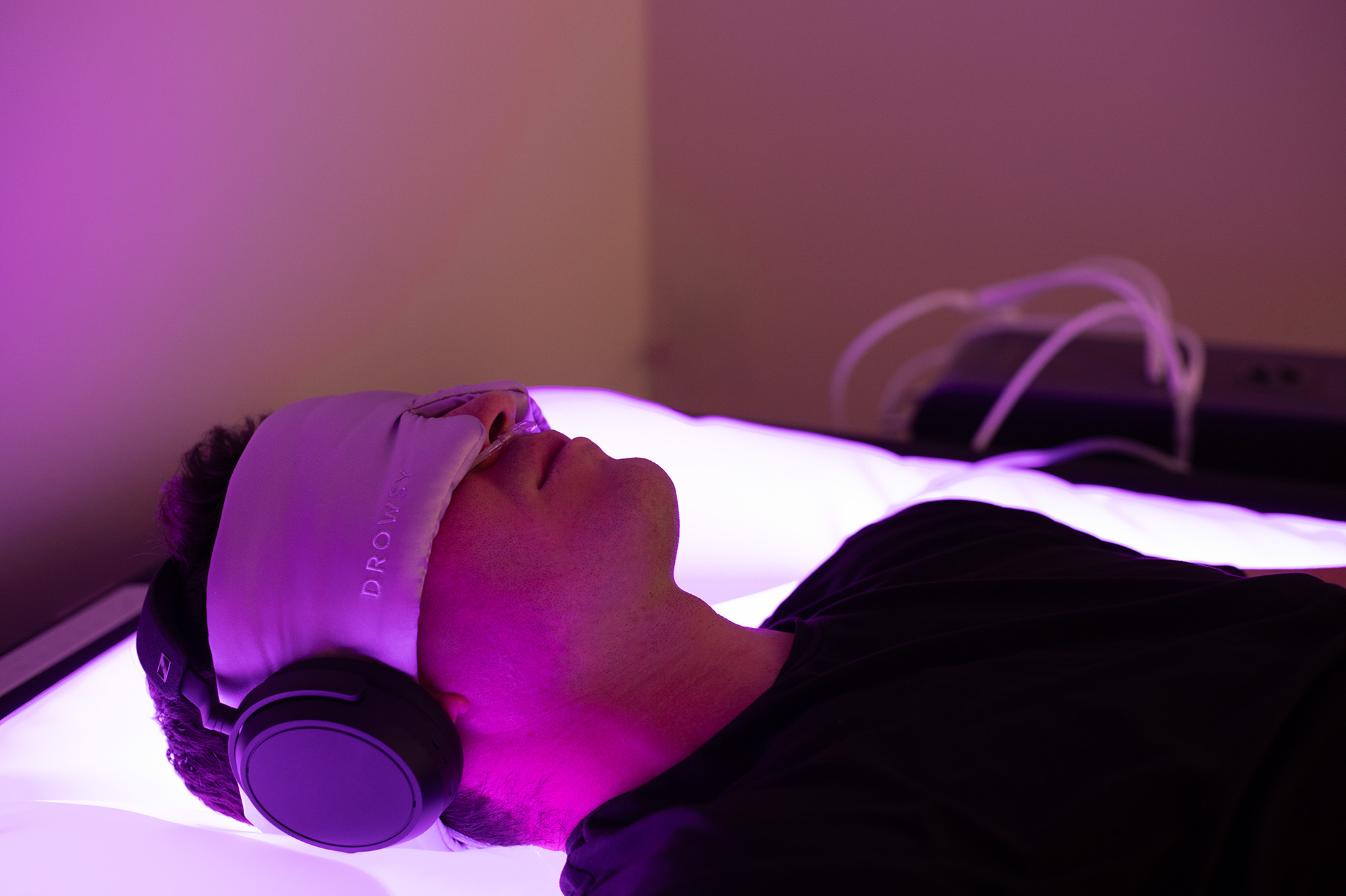Person relaxing in the ZenFloat under purple light, wearing headphones